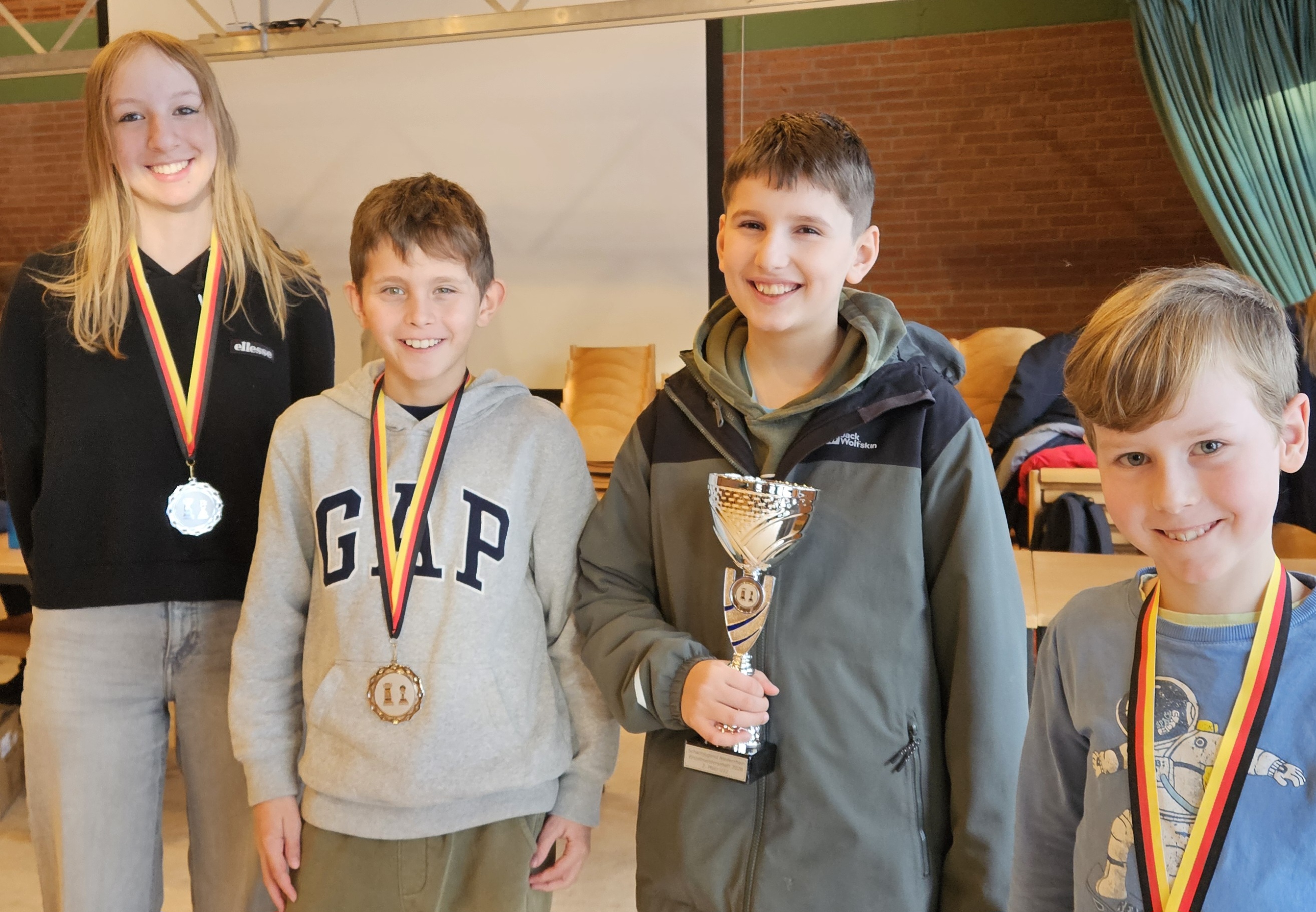 Ein Bild unserer vier Jugendlichen mit Medaillen und Pokal